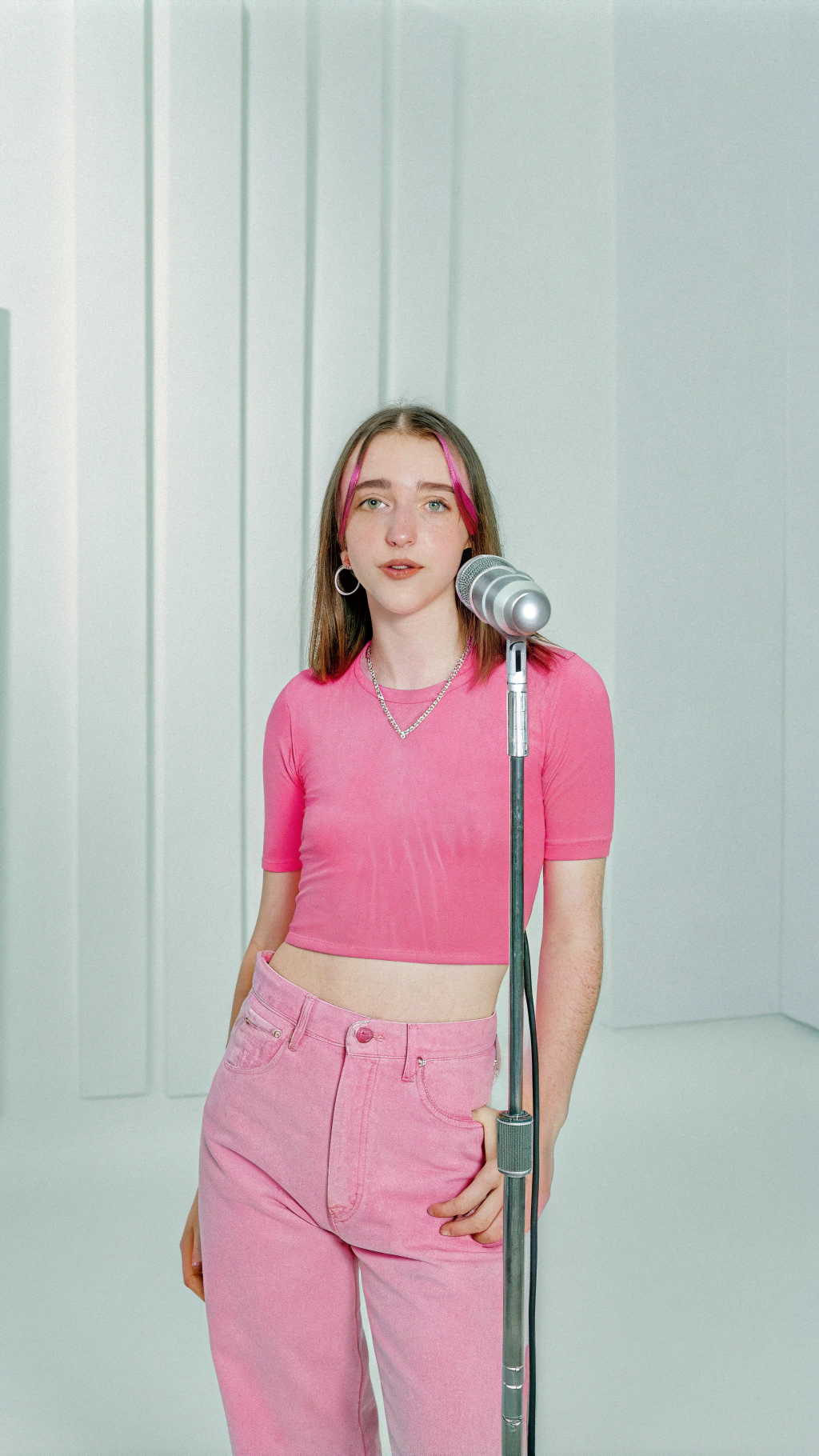 AI generated image by Red Panda AI: "Generate an ultra-realistic image of a beautiful 15-year-old girl in a modern recording studio, standing confidently in front of a microphone, ready to sing. The studio is well-lit with soft, diffused lighting and acoustic panels. She has a natural, youthful beauty with large, expressive brown eyes, smooth olive-toned skin, and soft, full lips with a subtle gloss. Her hair is shoulder-length, brown with light highlights, and styled in loose waves. She wears a fitted, pastel-colored crop top and high-waisted jeans, with small silver stud earrings. Her posture is relaxed but prepared, showing her focus and passion for music.