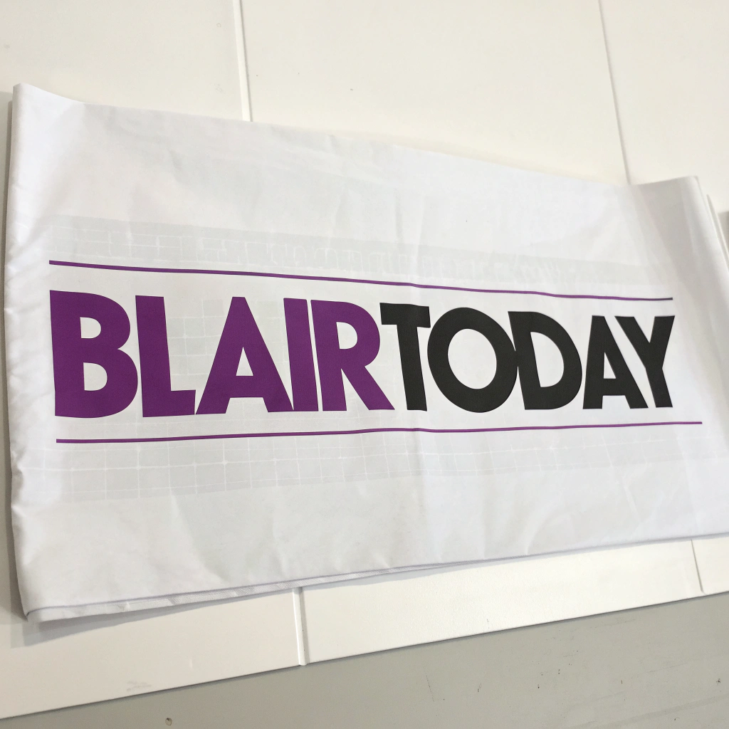 AI generated image by Red Panda AI: Logo for a blair, nebraska newspaper with a newspaper or writing theme called "BlairToday".  Using colors of purple and black are good.  The logo should be on white background