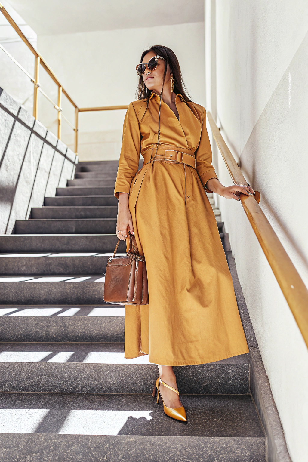 AI generated image by Red Panda AI: A 28-year-old slim European woman stands confidently in a stylish brown dress. Urban background, soft natural lighting, elegant heels, minimalistic jewelry, and leather handbag complete her look. standing at full height, full-body shot, head-to-toe view, entire outfit visible