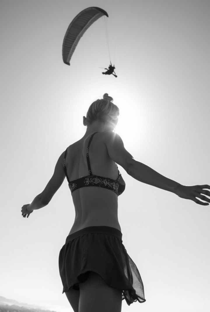 AI generated image by FLUX-Realism-Lora: Black and white photo of bare back woman in short skirt from behind swinging her bra above. a paraglider flying above her. Sky background. Backlight