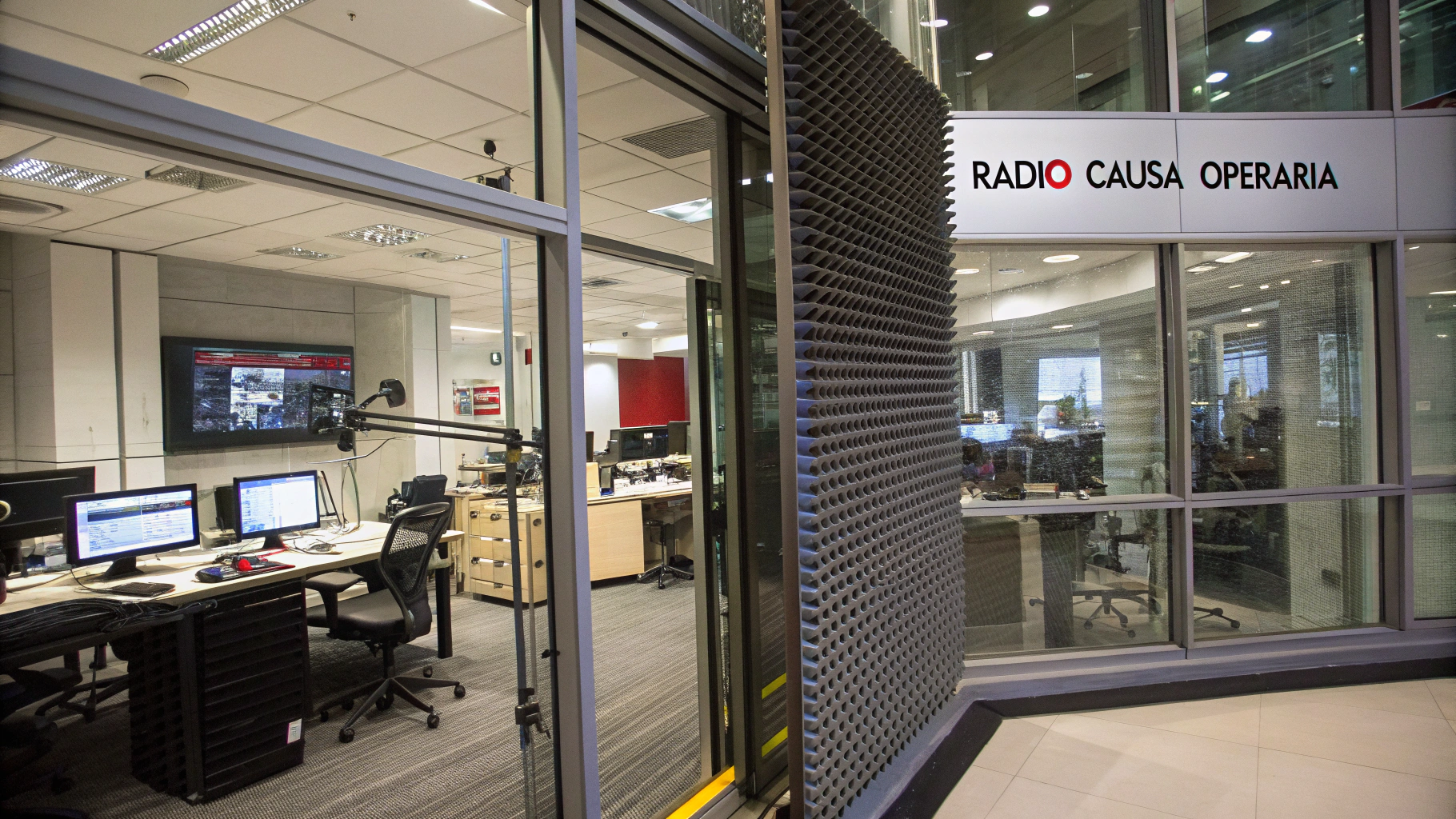 AI generated image by Red Panda AI: Radio Studio with glass walls, with some metal decorations and acoustic foam, behind the glass, in the far background, walls there is a newsroom,, with multiple PC monitors and desks, as wells as large TV that shows a news background with the Writing "Rádio Causa Operária". Image is a background, seen from the front. It shows no floor, and its lighting is all artificial.