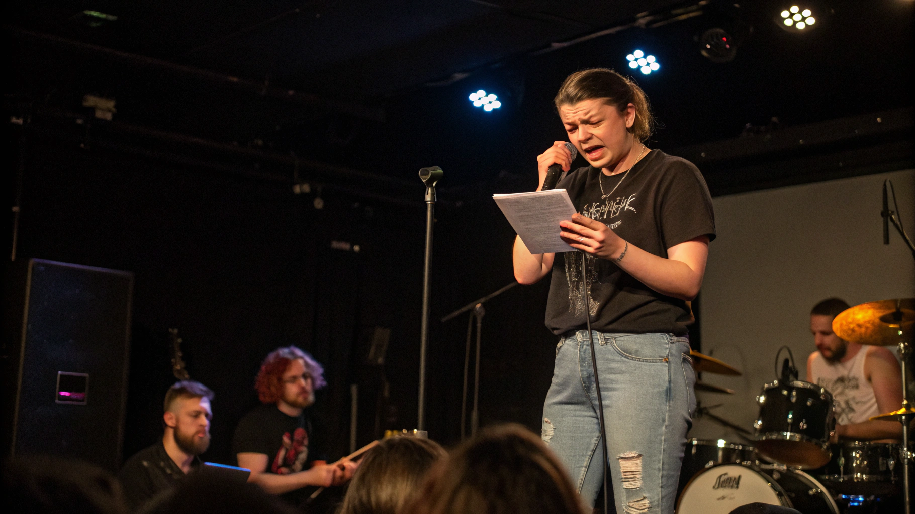 AI generated image by Red Panda AI: Singer stands on stage reading lyrics from a an iPad.  The singer looks confused.  The band and crowd are angry.