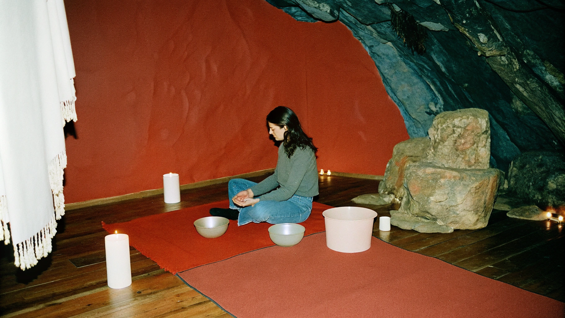 AI generated image by Red Panda AI:  retreat set in a mountain cave illuminated by soft candlelight, where a sound healer uses crystal bowls to create a meditative atmosphere. The natural rock formations of the cave amplify the vibrations, filling the space with resonant, calming sound.”
