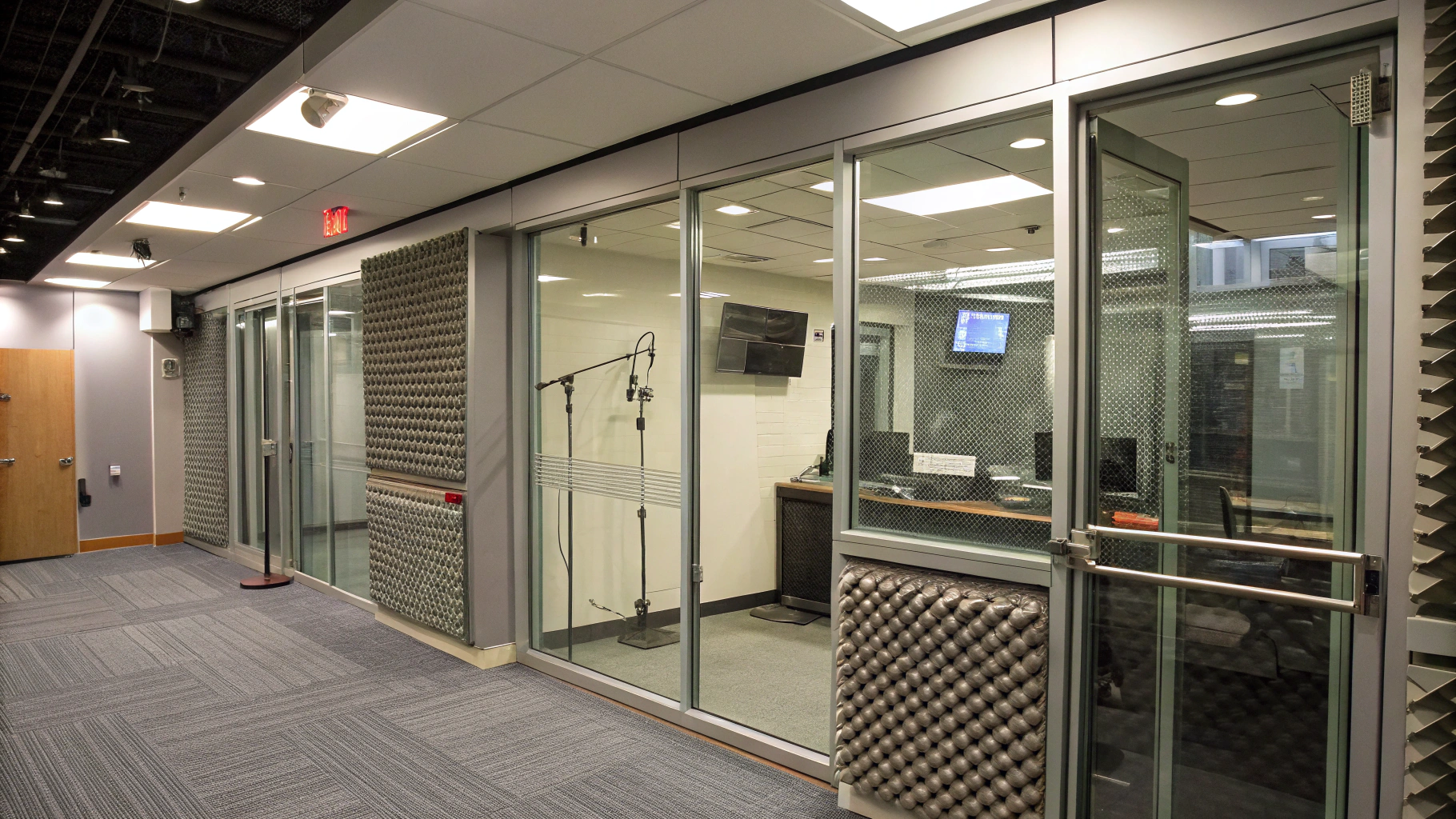 AI generated image by Red Panda AI: Radio Studio with glass walls, with some metal decorations and acoustic foam. Image is a background, seen from the front, like a 2d image. It does not show any floor, and its lighting is all artificial.