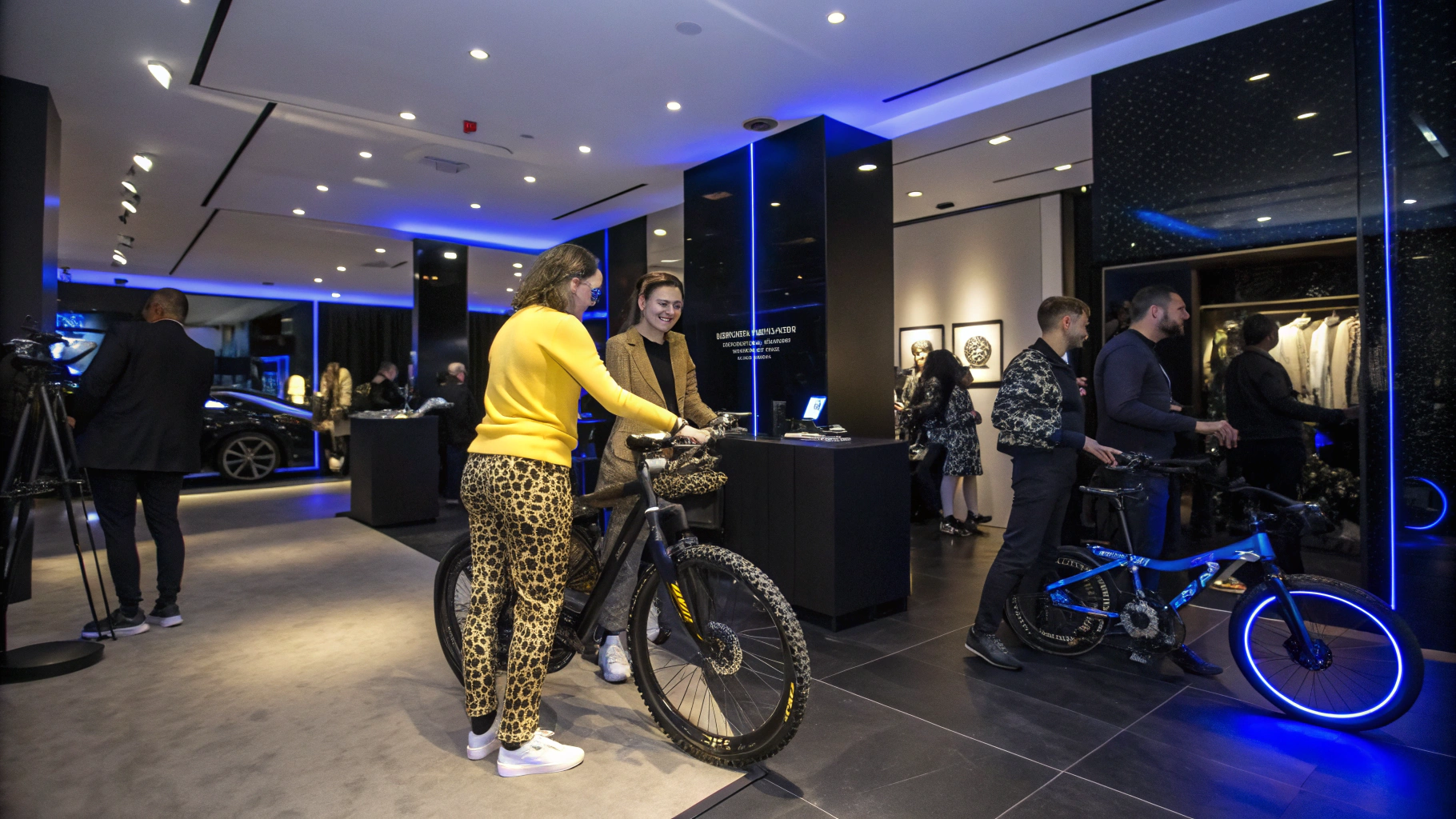 AI generated image by Red Panda AI: Adapted Prompt for High-Tech E-Bike Boutique:

“Create a highly realistic image of a luxury e-bike event held in an upscale boutique with a high-tech, dark ambiance accented by blue LED lighting. Include a person wearing a yellow top with leopard-print pants, smiling and interacting with others at the event. This person should be next to a matching e-bike with a leopard pattern. The event should feature various custom e-bikes with their owners, showcasing bold and unique designs, such as one attendee with a Japanese-patterned e-bike. The boutique’s interior should be modern and elegant, incorporating advanced tech elements and a prominent 3D customization booth. Groups of attendees should be engaged in conversation, and the overall atmosphere should be joyful yet luxurious, with lighting and decor that highlights the vibrant and custom designs of the e-bikes.”