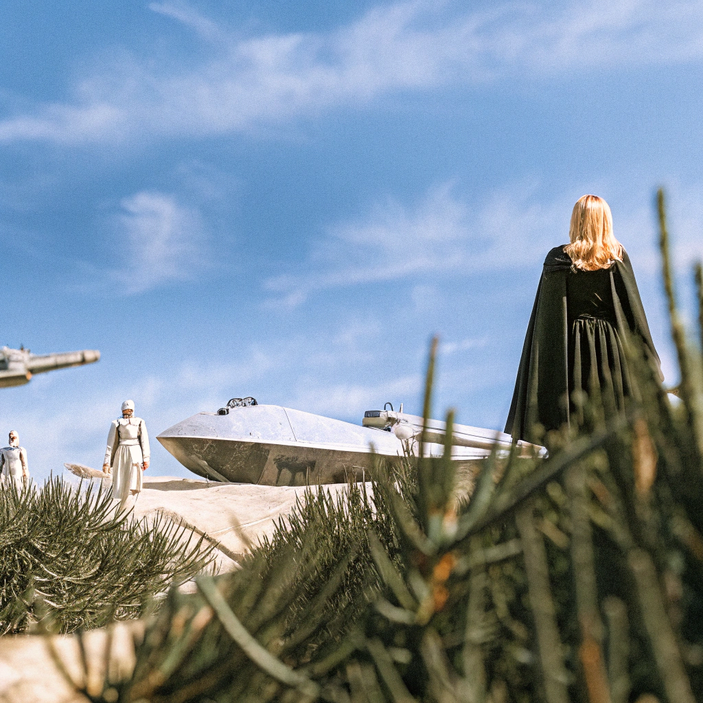 AI generated image by Red Panda AI: Genera una imagen de spensa del libro escuadron de brandon sardenson 
ella tiene pelo rubio con capa negra y un vestido y de fondo naves y un ambiente realista