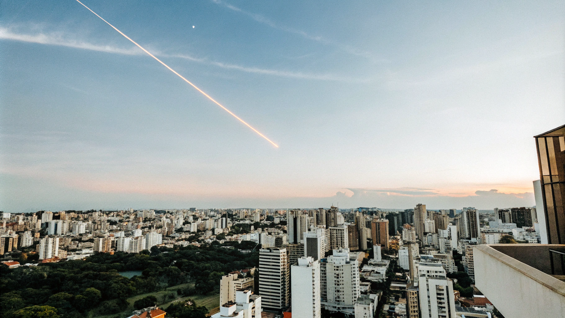 AI generated image by Red Panda AI: Ultra-realistic, cinematic aerial view of São Paulo at 6:20 PM during civil twilight. The cityscape stretches into the distance, illuminated by a stunning gradient sky transitioning from deep purple to warm orange. A vivid magenta-pink comet streaks diagonally across the sky, casting a faint glow over the modern skyscrapers and city lights beginning to flicker on. The horizon showcases the intricate urban sprawl with crisp details and realistic textures, inspired by high-quality astrophotography