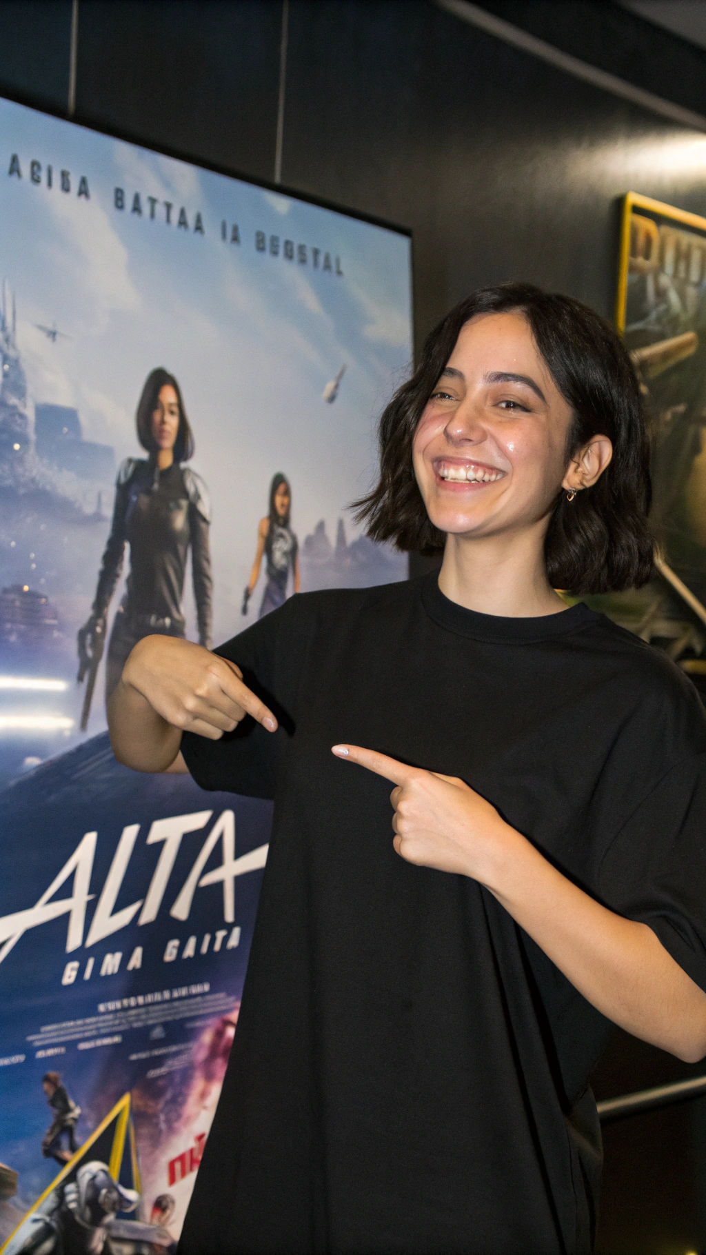 AI generated image by Red Panda AI: the character from the animation Alita, wearing a plain black t-shirt, with scenes from the film Alita, smiling at the camera and pointing at the t-shirt